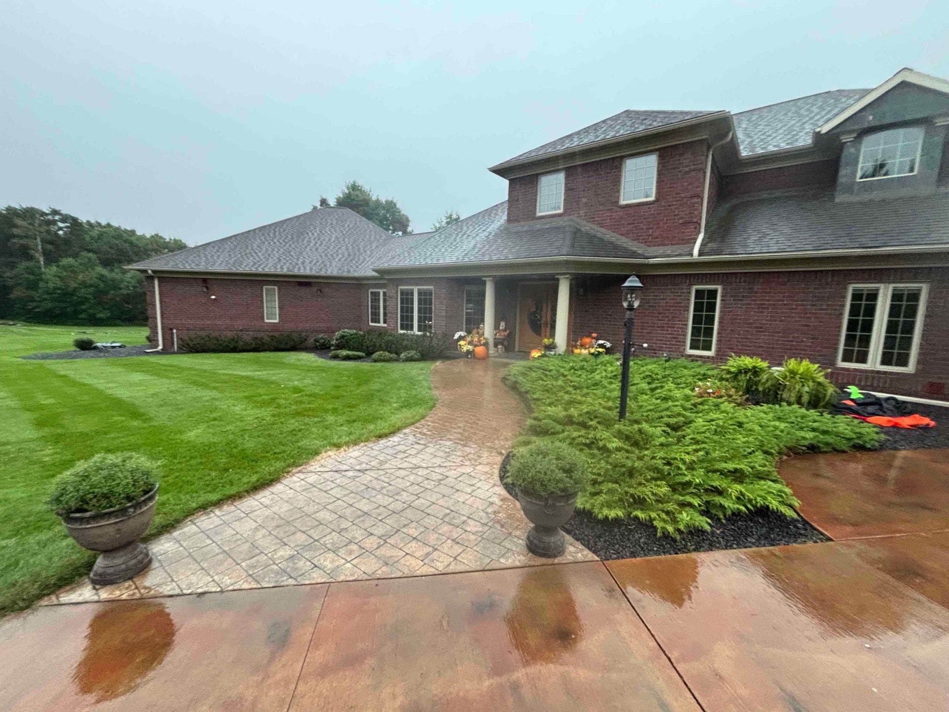 Finished front entry landscaping with paver walkways, healthy shrubs and decorative rock by No Plan LLC